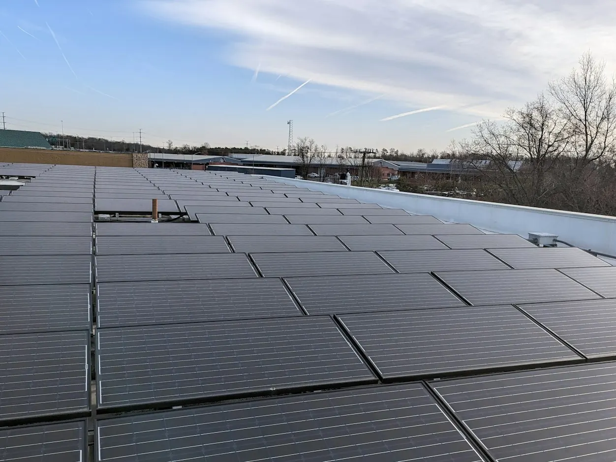 Large flat commercial roof covered with rows of solar panels