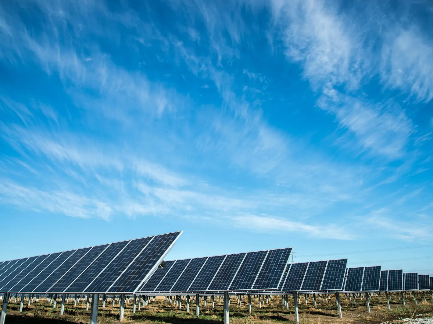 Ground-mounted solar array in a field under a wide blue sky
