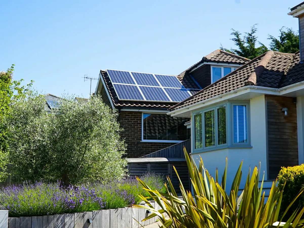 Two-storey house with solar panels on the roof behind a planted front garden