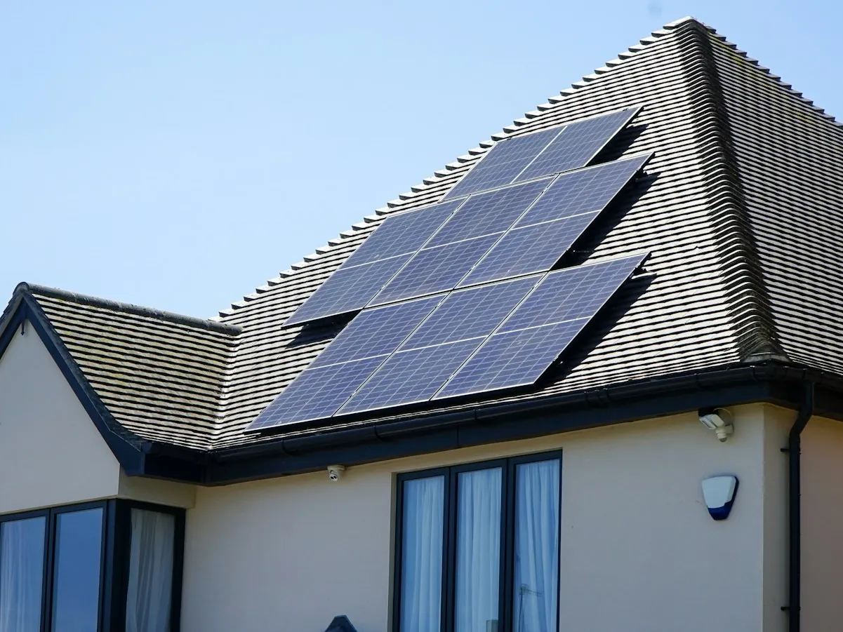 Modern home with a row of solar panels on a dark tiled roof