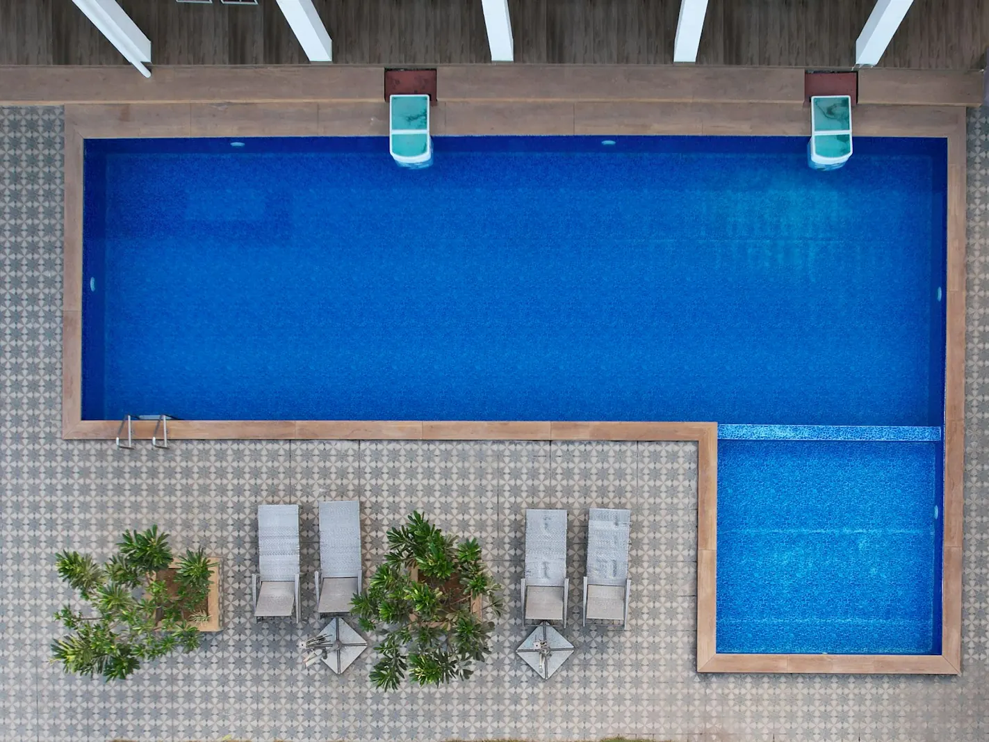 Aerial view of a rectangular swimming pool with sun loungers and potted plants