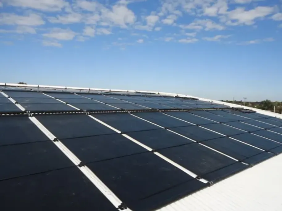 Dark solar pool-heating collectors laid across a sunny rooftop