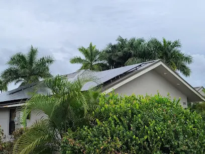 Single-storey home with solar panels on the roof, framed by palm trees and tropical shrubs